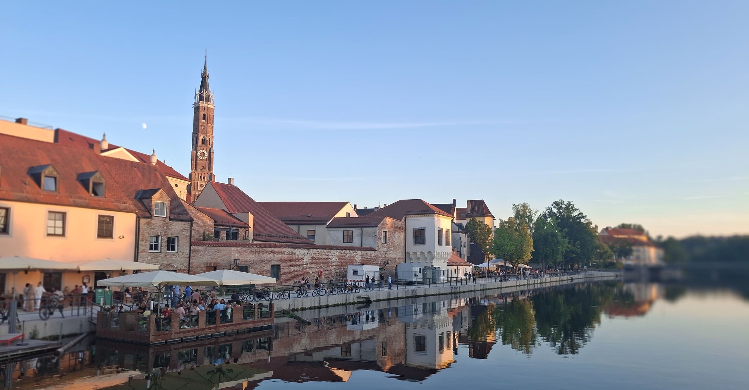 Straßencafés und historische Häuser an der Isar in Landshut mit Blick auf den Kirchturm von St. Martin